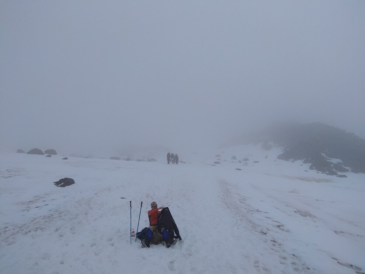 Коллега-восходитель пытается надеть тёплую куртку