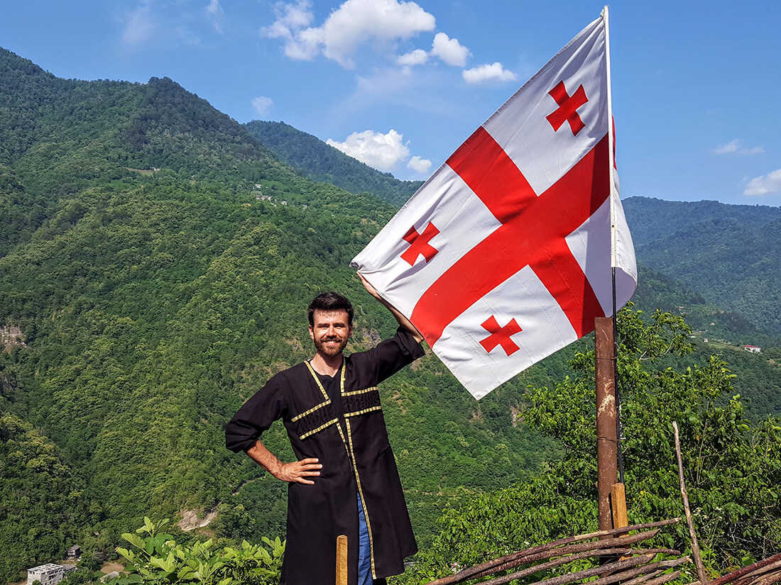 поехал в отпуск без путёвки, поставили у флага и нарядили. еще и гору поставили на фоне