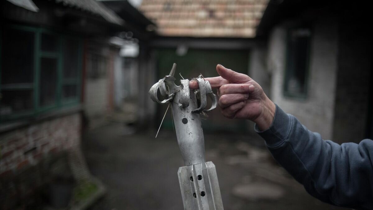    Женщина демонстрирует осколок мины во дворе жилого дома в поселке Зайцево Донецкой области.© РИА Новости / Валерий Мельников