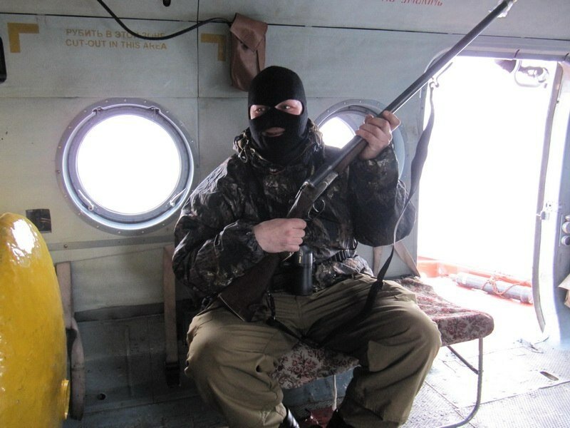 На вертолете участник экспедиции по "Очистке Арктики" летит на остров Греэм-Белл. На нем надета балаклава.