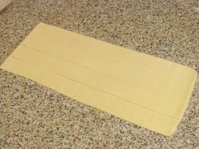     Для начала нужно разморозить слоёное тесто при комнатной температуре. Затем посыпьте мукой твердую поверхность для того, чтобы слоеное тесто не прилипало к поверхности и раскатайте его. Тесто должно быть толщиной около 4-5 мм. Потом разрежьте его по вертикали так, чтобы полоски были длинными, а их ширина составляла примерно 2 см.    