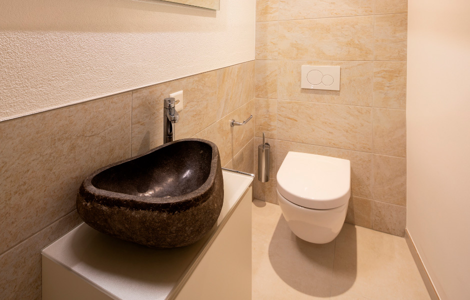 Минимализм может быть разнообразным. В данном случае акцент в интерьере создает верхняя часть стены, отделанная фактурной штукатуркой, и раковина темно-коричневого цвета.