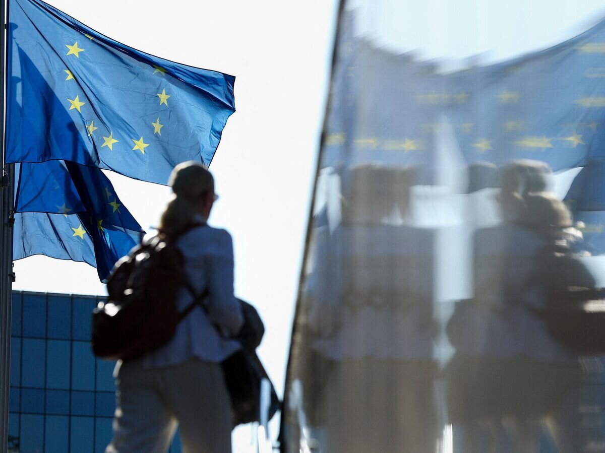    Женщина проходит мимо флагов ЕС в Брюсселе © AFP 2023 / Kenzo Tribouillard