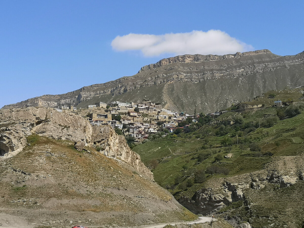 С другой стороны над нами нависало село Чох, отлично вписанное в ландшафт пиков и хребтов Кавказских гор. Что касается самой дороги, то она извилистая, без асфальтобетонного покрытия, но вполне ещё приемлемая для проезда. Добираемся до подножия горы, на которой стоит Гамсутль. Село снизу почти не видно. Оставляем автомобиль и начинаем подъем. Для туристов есть несколько способов добраться наверх. Самый бюджетный, который мы выбрали —  пешком. 