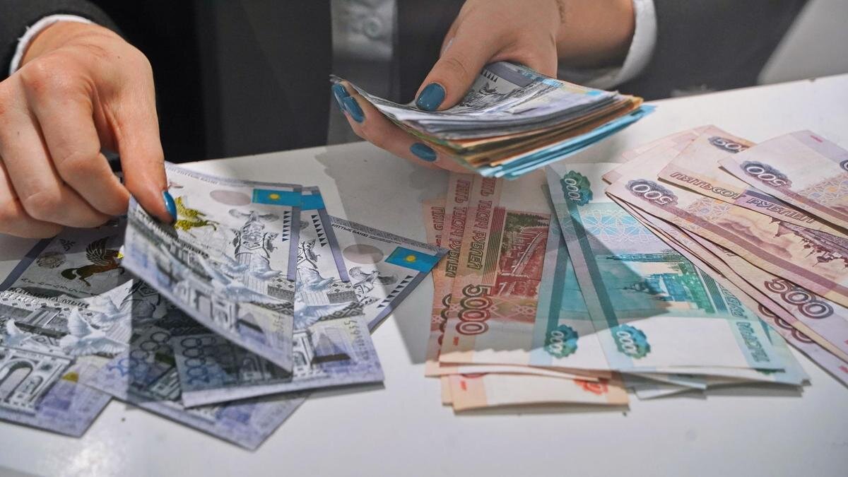    Кассир раскладывает купюры тенге рядом с рублями:NUR.KZ / Владимир Третьяков