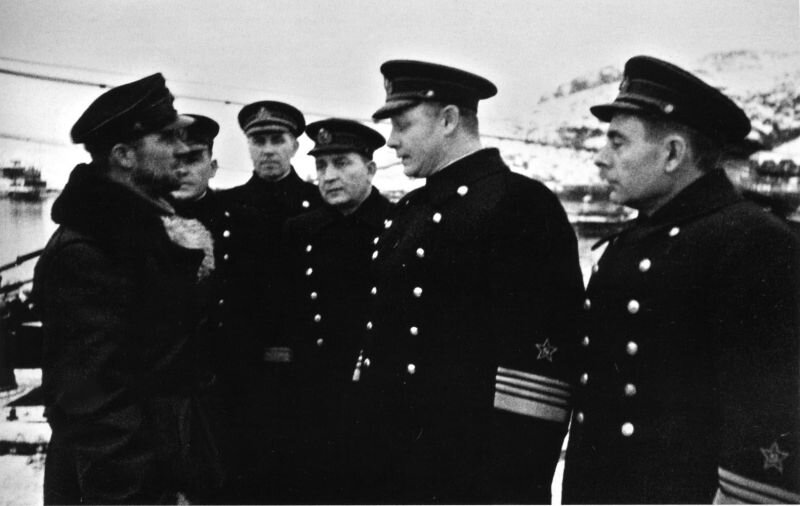Адмирал Николай Герасимович Кузнецов (1904-1974), главнокомандующий ВМФ СССР, и вице-адмирал Арсений Григорьевич Головко (1906-1962, крайний справа), командующий Северным флотом, беседуют с командиром подводной лодки Щ-403 капитан-лейтенантом Константином Матвеевичем Шуйским (1907-1943). Слева направо: капитан-лейтенант К.М. Шуйский, командир бригады подводных лодок Северного флота (БПЛ) контр-адмирал Н.И. Виноградов, неизвестный (скорее всего, военком БПЛ капитан 2 ранга В.К. Болдырев), адмирал А.А. Николаев, адмирал Н.Г. Кузнецов и вице-адмирал А.Г. Головко.