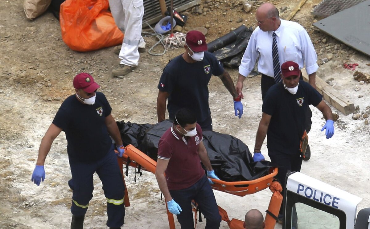 Следователи Кипрской группы реагирования на стихийные бедствия несут покрытый чемодан на носилках после того, как его извлекли из искусственного озера недалеко от деревни Мицеро, недалеко от столицы Никосии, Кипр, во вторник, 4 июня 2019 года. 