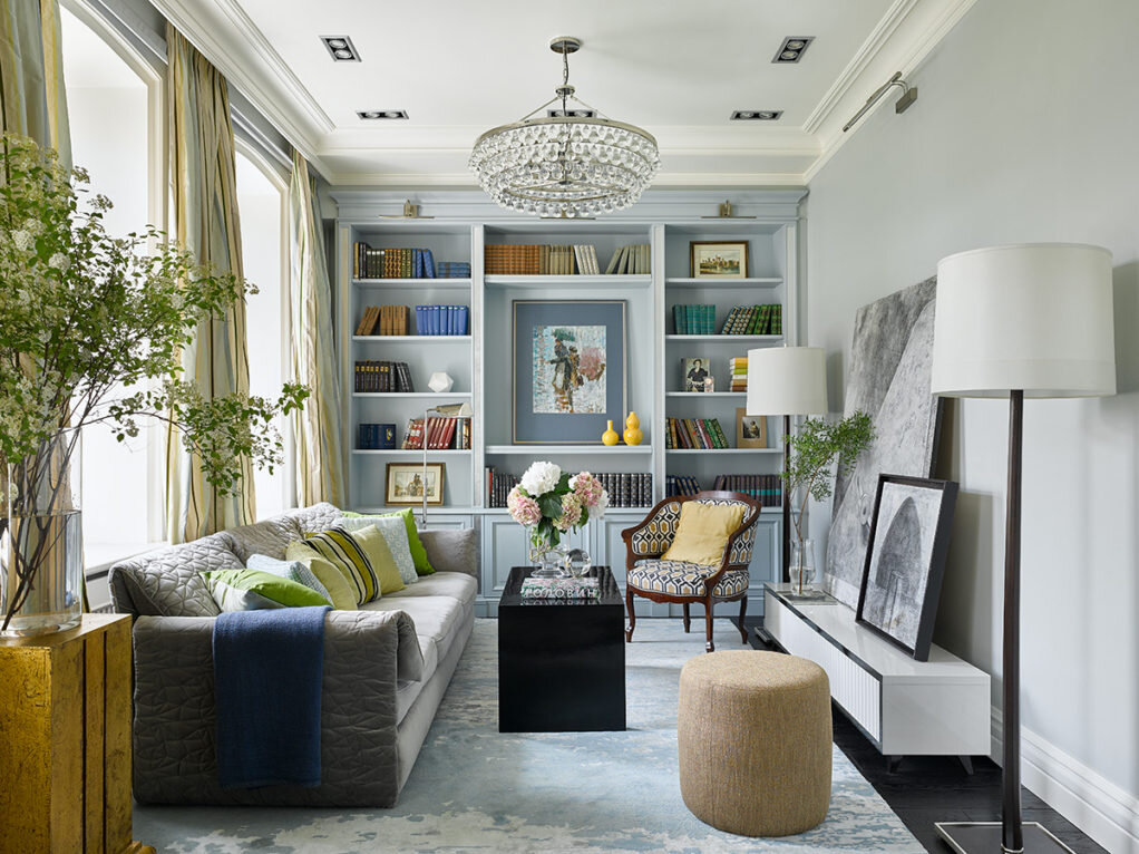 Гостиная. Квартира находится в дореволюционном доме, это расселенная коммуналка на последнем этаже, там много света и воздуха. По словам Инны Зольтманн, ей хотелось передать дух старой Москвы, но в современном звучании. Встроенная библиотека сделана по эскизам автора проекта в столярной мастерской Attribute. Диван, Kenzo Maison, салон "Трио-интерьер". Антикварное кресло и винтажный столик, Мастерская Кати Гердт. Графика, Екатерина Рожкова. Торшеры – Barbara Barry, Design Place. Люстра, Robert Abbey, Design Place. Флористика – Садовый центр Людмилы Боголюбовой. Шторы сшиты из шелка Pierre Frey (основа колористики проекта). Подушки, пледы – Лаборатория текстиля для дома Лоффилаб. Пуф, IDC Collection. Тумба под ТВ изготовлена по эскизам декоратора в мастерской AEON GROVE, руководитель Хаджи-Мурат Дудов. Ковер Art de vivre. Гипсовый потолочный карниз изготовлен по эскизам автора проекта компанией "Технология отделки", руководитель Артем Халиков.