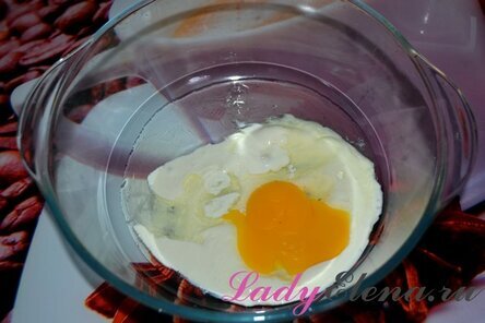 Сначала нужно приготовить тесто. Для этого в пустую миску выложить сметану (100 г). Разбить туда же яйцо.
