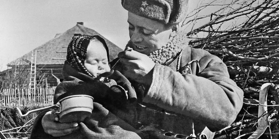 История трогательного фото, на котором советский солдат кормит маленькую девочку, которую он спас