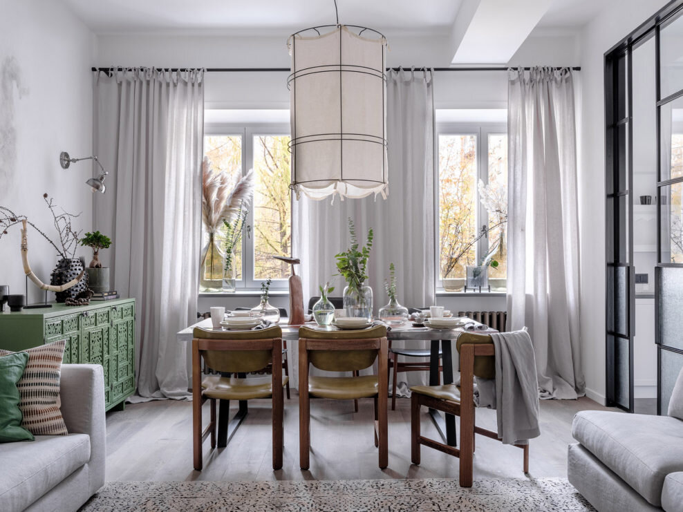 Зона столовой. Стулья винтажные, “Мебельдом”; светильник сделан на заказ, Svetoalliance; посуда на столе, “Дымов Керамика”; шторы, Linen Texture; декоративные элементы и плед, Moon-stores. Справа, за раздвижными стеклянными перегородками, Makeloft, находится кухня.