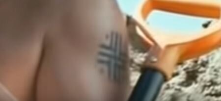 Татуировка на плече в виде стилизованного символа свастики