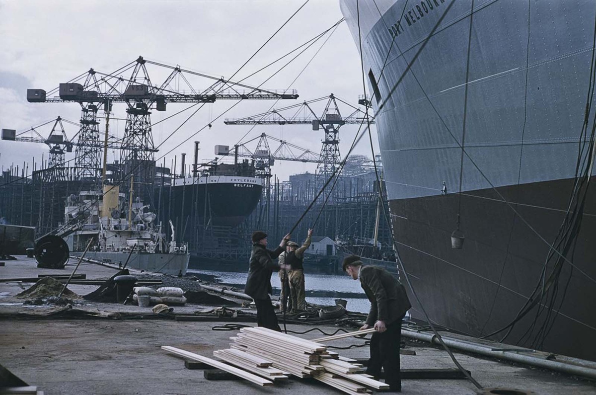 Грузовое судно Port Melbourne (справа) строится на верфи Harland & Wolff. Позже корабль был переименован в Princess Danae. На заднем плане - строящееся грузовое судно Foylebank (позже Patroclos). 
