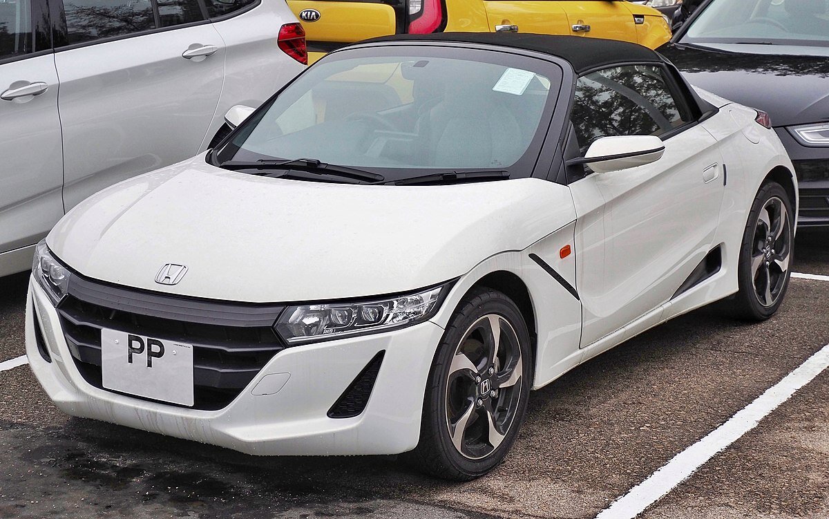 Honda s660
Японская компания Хонда пока для внутреннего рынка выпустила Honda S660. Изначально публика увидела в 2013-м году концепт, происходил показ в Токио. Спустя два года была выпущена серийная модель, которая не так уж сильно отличалась от концепта.
Форма задней части Honda S660 напоминает суперкары, будто здесь установлен очень мощный мотор. Задняя узкая оптика также имеет светодиодную начинку – выглядит неплохо. Задний бампер более массивный, на нем есть огромные воздуховоды из задних тормозов, а посередине расположился один патрубок системы выпуска.
Коробок передач две на выбор: «механика» на шесть ступеней (впервые в классе, утверждает компания, мол, раньше у таких малышей было только пять) или вариатор с ручным режимом, имитирующим семь виртуальных передач, и переключением подрулевыми лепестками. Средний расход топлива — 4,7 л/100 км с «механикой» и 4,1 л/100 км с вариатором. Ёмкость топливного бака — 25 л