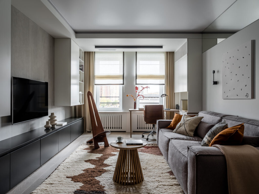 Гостиная. Встроенная мебель выполнена на заказ по эскизам авторов проекта; рабочее кресло, TopChairs Crown; диван, SK Design; журнальный стол, La Forma (Fields); деревянный стул-кресло винтажный; бра, Pulssar; настольная лампа, Muuto (L'appartement); аксессуары, L'appartement, IKEA, Nomad Chic, H&M. Над диваном картина Александры Дашкевич “Хаос”; шторы, Елена Дашкевич; ковер, Nomad Chic; инженерная доска, Finex; на стене за телевизором широкоформатный керамогранит, Laminam.