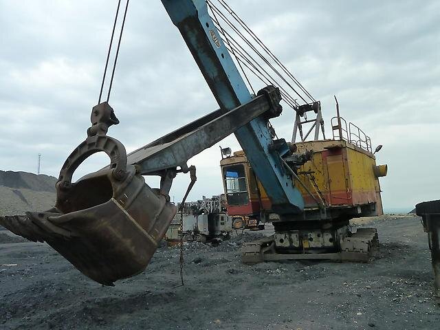 Производство и изготовление запчастей для карьерных экскаваторов  ЭКГ-5, ЭКГ 8, ЭКГ-10, ЭКГ-12,5, ЭКГ-15:  СпецДорТрак: https://trak74.ru/jekg-2/ © Запчасти для спецтехники

В горных промышленностях и месторождениях используется довольно большая и очень тяжелая специальная техника, так как обычные экскаваторы, даже достаточно мощные современные модели, не способны справиться с такой нагрузкой. Для проделывания погрузочных работ различных горных пород был разработан большой и довольно мощный экскаватор, а именно это ЭКГ-5А (первые образцы были выпущены еще в 1980 году). Сама же аббревиатура данной машины расшифровывается, как Экскаватор, Карьерный, Гусеничный. Присутствие в названии цифр дает понять: сколько способен вместить в себя ковш. В данном же случае он рассчитан на пять кубических метров, что позволяет загрузить кузов грузовой машины БелАЗ всего за три-четыре подхода. Но также немало интересным фактом об этом экскаватора является то, что для работы он использует дизельный двигатель, как практически все другие специальные машины, а электрические двигатели. Всего на борту ЭКГ-5А установлено шесть электродвигателей, самый мощный из них развивает мощность в 250 киловатт, что в переводе на лошадиные силы составляет 340 лошадиных сил. Их суммарная мощность достигает отметки в 622 киловатта или же в 845 лошадиных сил. Данная силовая установка развивает 550 метров в час, что хоть и является очень низким значением, но при массе экскаватора в 197 тысяч килограмм (с учетом всех установленных противовесов) этого вполне достаточно. Всего было выпущено около 15 тысяч машин, которые нашли свое применение практически по всему миру, начиная от Мозамбика и заканчивая Кубой. Но в основном данная техника используется в России, в работе на всех месторождениях.


Назначение

 
Как было упомянуто ранее, из одного только названия машины ЭКГ-5А, можно понять, что данная техника предназначена исключительно для работы в горных промышленностях. Большая мощность экскаватора и высокая прочность позволяет ему проводить погрузочные работы тяжелых горных пород, конечно, предварительно раздробленных. Помимо этого он еще выполняет и землеройные работы тяжелого грунта и твердых фракций. Из всего этого можно сделать вывод, что экскаватор ЭКГ-5А является незаменимой машиной в металлургии, добыче угольных пород и других полезных ископаемых, а также и в строительных отраслях (имеется ввиду подготовка карьеров и другие масштабные операции).


Навесное оборудование
Все его рабочее оборудование состоит из двуногой стойки, стрелы, системы открывающей ковш и рукоятки самого ковша. Этот экскаватор не имеет гидравлической системы, поэтому все элементы оборудования управляются тросами, которые в свою очередь оказывают действие за счет тех же самых электрических двигателей.

Из навесных же агрегатов, данный экскаватор изначально применяет в работе лишь пяти кубовый ковш, который по стандарту имеет сменные зубья. Этот ковш неподвижно установлен к рукояти, а сам процесс выгрузки груза происходит за счет открытия задней стенки. Толщина каждой стороны этого ковша составляет почти пять сантиметров. Объем ковша в пять кубических метров, позволяет за подход загрузить массу в 12 тысяч килограмм.

Модификации

Экскаватор ЭКГ-5А имеет не так уж и много модифицированных версий, а именно всего три машины. Каких-либо отличий в плане внешнего вида все версии не имеют, но имеются изменения, касающиеся технических характеристик и его возможностей. Разберем отличия каждой модификации подробно:

Модификация ЭКГ-5В. Вместимость ковша у данной версии имеет такое же значение, что и у базового экскаватора, а именно это пять кубических метров. Ковш оборудован пневмоударными зубьями, которые позволяют разрушать горну и другую твердую массу в процессе черпания. Благодаря этому пропадает необходимость применять другую технику, а также взрывы пород для их рыхления. В целом, данная модификация и рассчитана на работу в тех местах, где по каким-либо причинам недопустимо бурение и взрывные работы. Установлена пневматическая система.
Модификация ЭКГ-5Д. Ключевой особенностью этой модификации является то, что машине больше не нужно тащить за собой метры проводов. И этому есть свое объяснение: на экскаваторе установлено несколько дизельных двигателей, которые выступают в роли электрогенератора, обеспечивая необходимым напряжением основные электродвигатели. Топливный бак для этих силовых агрегатов вмещает в себе 3800 литров дизельного топлива, что позволяет проводить работу более 24 часов без каких-либо остановок. Контролируется работа генераторов в кабине, с помощью специальных датчиков и приборов. Также, в отличие от базовой модели экскаватора, в этой могут быть установлены гусеницы большей ширины.
Модификация ЭКГ-5А-УС. В этой модели установлен ковш, объем которого составляет 4600 кубических сантиметров. Благодаря удлиненному рабочему оборудованию, данная машина способна проделывать работу по погрузке пород в железнодорожные вагоны (с учетом их расположения на уровне стоянки ЭКГ) или же в грузовые машины, габариты которых намного больше обычных карьерных автосамосвалов. Также как и базовый экскаватор, данная модель использует лишь электродвигатели для осуществления карьерных задач.

Технические характеристики
Гусеничная рама экскаватора обладает массой в 5450 килограмм. Длина этой рамы составляет 3000 миллиметров, ширина равняется так же 3000 миллиметрам, ну а высота составляет 1680 миллиметров. Нижняя рама имеет вес в 10500 килограмм. Длина нижней рамы обладает значением в 5500 миллиметров, ширина имеет значение в 750 миллиметров, высота составляет ровно 1000 миллиметров. Длина гусеничного хода составляет 5830 миллиметров. Устанавливаются гусеницы трех размеров, ширина которых составляет 900 миллиметров, 1100 миллиметров или же 1400 миллиметров.

Масса поворотной рамы доходит до 18900 килограмм. Длина, от края и до края, равняется 8100 миллиметрам. Ширина составляет ровно 5000 миллиметров. Высота обладает значением в 1200 миллиметров.

Кабина данной машины весит 1100 килограмм. Ее длина составляет 2360 миллиметров. Ширина составляет 1350 миллиметров. Высота равняется 2760 миллиметрам.

Масса двуногой стойки (она же стрела) базовой модели экскаватора обладает значением в 3480 килограмм. Длина стойки составляет 6450 миллиметров, а ширина 1400 миллиметров.

Рукоятка ковша в длину составляет 7915 миллиметров. В ширину составляет 1774 миллиметра. Ее масса обладает значением в 7950 килограмм.

Вес ковша составляет 9935 килограмм. Толщина стенок составляет не более пяти сантиметров. Длина равняется 2450 миллиметрам, ширина 2190 миллиметрам, ну а высота 2560 миллиметрам. Сам же ковш состоит из следующих частей: передние и задние стенки, коромысла и несколько обойм, имеющие уравнительный блок. Ковш полностью изготовлен из высокопрочной марганцовой стали, но для полной устойчивости к ударам покрывается твердым сплавом. Имеется пять съемных зубьев (в модификации ЭКГ-5Д устанавливаются пневматические отбойные зубья), которые также покрыты твердым сплавом.

Максимальный радиус черпания составляет 14500 сантиметров. Максимальная высота выгрузки груза обладает значением в 6500 сантиметров. Максимальный радиус выгрузки составляет 12650 миллиметров. Дорожный просвет под поворотной платформой 1890 сантиметров. Экскаватор ЭКГ-5А со всеми установленными противовесами имеет массу в 197 тысяч килограмм.

Установлено шесть электродвигателей, выдающих суммарную мощность в 622 киловатта или же 845 лошадиных сил. Самый слабый из этих агрегатов выдает мощность ровно в 50 киловатт, что в переводе составляет около 68 лошадиных сил. Самый мощный среди остальных способен выдать мощность в 250 киловатт, это составляет 340 лошадиных сил. На модификацию ЭКГ-5Д устанавливается еще и несколько дизельных силовых агрегатов, позволяющие экскаватору выработать необходимое для полноценной работы напряжение. В таком случае, на экскаватор устанавливается топливный бак, объемом в 3800 литров горючего.

Экскаватор может взобраться на подъем, угол которого не более 12-ти градусов.


Особенности
Из ключевых особенностей необходимо отметить эффективность данного экскаватора, так как за счет пяти кубового ковша, кузов грузовой машины БелАЗ может быть полностью заполнен породой и другим грузом всего за пару подходов. Одной модифицированной версии устанавливается пневматическая система, которая нужна для использования отбойных зубьев ковша. Как было упомянуто ранее, это позволяет рушить породу при самом черпании. Данная возможность является полезной в таких ситуациях, когда применение другой специальной техники, а именно бурильного оборудования по каким-либо причинам недопустимо.

Дальнейшее обслуживание данной техники не вызовет особых денежных затрат, да и времени на поиски неисправностей. Конструкция машины довольно проста, так как детали и механизмы каждого двигателя расположены отдельно относительно друг друга (установленных рядом двигателей), что как раз и обеспечивает быструю находку появившихся неполадок.



Двигатель
Вся силовая установка базового экскаватора ЭКГ-5А состоит из шести электрических двигателей. Самый слабый из них выдает 50 киловатт или же 68 лошадиных сил, когда самый мощный способен развить 250 киловатт (340 лошадей). Суммарная мощность всех агрегатов составляет 622 киловатта (845 лошадиных сил).


Цена нового и б/у
На данный момент стоимость на новый экскаватор ЭКГ-5А начинается от 14 миллионов российских рублей. Но цена может изменяться в зависимости от года выпуска и версии самой машины (модифицированная или же базовая).

Поддержанный ЭКГ-5А имеет стоимости значительно ниже, а именно от трех миллионов до пяти миллионов российских рублей. На стоимость машины влияют год производства, версия, и конечно же, техническое состояние.