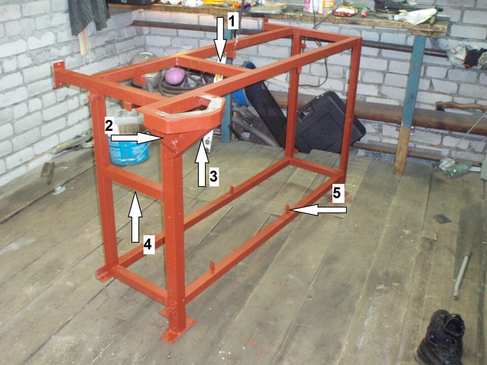 Варим раму верстака
Особое внимание я уделил фундаменту под тиски, его я сделал с выносом за пределы столешници, это нужно чтоб обеспечить пространство для работы. Фундамент выгнут из угольника 50х50 по форме присоединительной поверхности тисков и имеет большую жесткость, внутри одной из усиливающих книц вварена контактная пластина, она не окрашивается и нужна для подключения массы при необходимости сварки прямо в тисках. Раньше найти место для крокодила массы было настоящей проблемой. Перед окраской верстак необходимо собрать со всеми полками для примерки и пригонки, потом разобрать.
На фото:
— 1, 4 — усиливающая обвязка верстака для жесткости на кручение. Эти трубы предназначены распределять нагрузку на другие элементы при работе с тисками, например при гибке металла;
— 2, 3 — кницы для жесткости фундамента под тиски;
— 5 — крепления для перегородок.
Грунтуем