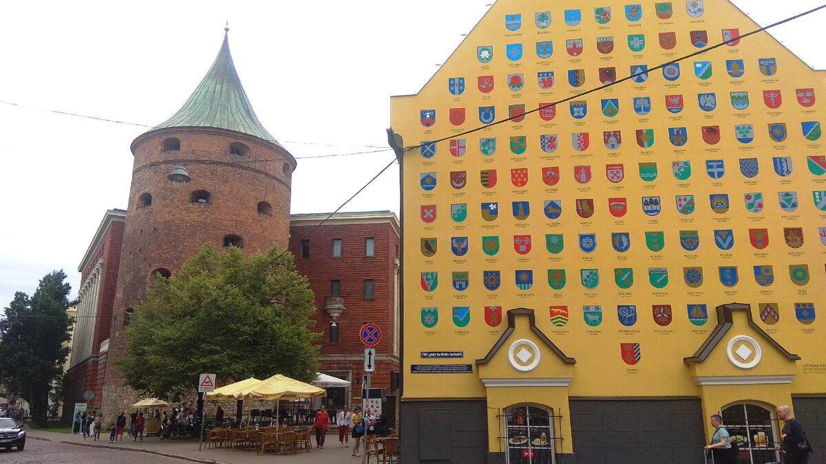 А это вид влево от казарм. Пороховая башня, единственная сохранившаяся до наших дней башня Цитадели, элемент системы городского укрепления Риги, в наши дни являющаяся филиалом Военного музея Латвии. А на торце здания казарм - гербы городов Латвии. От башни идут две улицы. Рядом с казармами, как уже говорил, Торня и - листайте дальше -