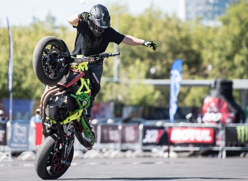 1) С ЧЕГО НАЧАТЬ? Начинающим спортсменам можно дать несколько крайне важных рекомендаций, которые помогут вам не разбиться после первой же тренировки. Абсолютно точно для этой цели вам не подойдут мощные мотоциклы — если вы плохо знаете их качества, то лучше на них не садиться. Вдобавок, вам крайне дорого обойдется ремонт. Для начальных тренировок возьмите бюджетный мотоцикл, который вам знаком.
Не начинайте тренировки с самых крутых трюков — можете сломать себе шею. В этом направлении лучше всего двигаться постепенно. Неплохо иметь опытного наставника, который при случае расскажет вам о недостатках вашего вождения. Также не следует заниматься этим в одиночку — можете с легкостью натворить проблем, а потом вас еще будет и некому доставить в ближайшее лечебное учреждение.
Стантрайдинг как вид спорта не стоит на месте — ежегодно происходят качественные изменения, добавляются новые трюки, а в уже существующие вносятся дополнительные детали. Столицей стантрайдинга в странах СНГ по достоинству считается Санкт-Петербург — именно здесь каждый год проходят соревнования по этому виду спорта. Чемпионаты, проходящие здесь регулярно с 2008 года, собирают все большую аудиторию.
В стантрайдинге существуют элементы, которые относятся к классическому трюкачеству, а также усложненные варианты, выполнить которые под силу лишь профессионалам своего дела. К ним относятся так называемые «вилли» и «стоппи» — базовые элементы начинающих спортсменов.

Особый вид мотоциклов или питбайков, имеют ряд существенных изменений в конструкции:

Наличие дуг, поскольку при падении возможно нарушение целостности пластика или других частей байка;
2. Обязательное отключение прибора, фиксирующего угол наклона транспортного средства;

3. Максимальная длина троса регулировки холостого хода;

4. Усиленное крепление радиатора, исключающее возможность его деформации в момент выполнения трюков;

5. Укрупненная задняя звездочка, позволяющая поднимать мотоцикл на заднее колесо с максимальным удобством для байкера;

6. Возможность с помощью рук включить вентилятор — подобное приспособление надежно помогает не перегревать двигатель;

7. Деформированный бак, позволяющий с максимальным удобством стоять на мотоцикле;

8. Максимально укороченная выхлопная труба — в обычном ее варианте — это возможная причина падения;

9. Усиленная подвеска, помогающая при окончании приема «вилли максимально удобно возвращаться в исходное положение, предотвращая падение.

10. Кроссовый руль — надежно обеспечит управляемость мотоциклом, а приборная панель расположится в месте, которое с наименьшей вероятностью может подвергнуться деформации при аварии;

Стантрайдинг имеет три вида трюков — остальные являются производными, зависящими от уровня квалификации мотоциклиста:

 1. Stoppie;

