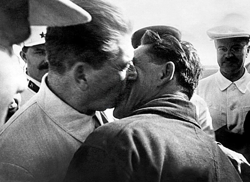Иосиф Сталин (слева) целует полярного летчика Василия Молокова (справа) по возвращении в Москву вместе с Отто Шмидтом (не на фото), исследователем Арктики 4 июля 1937 года.