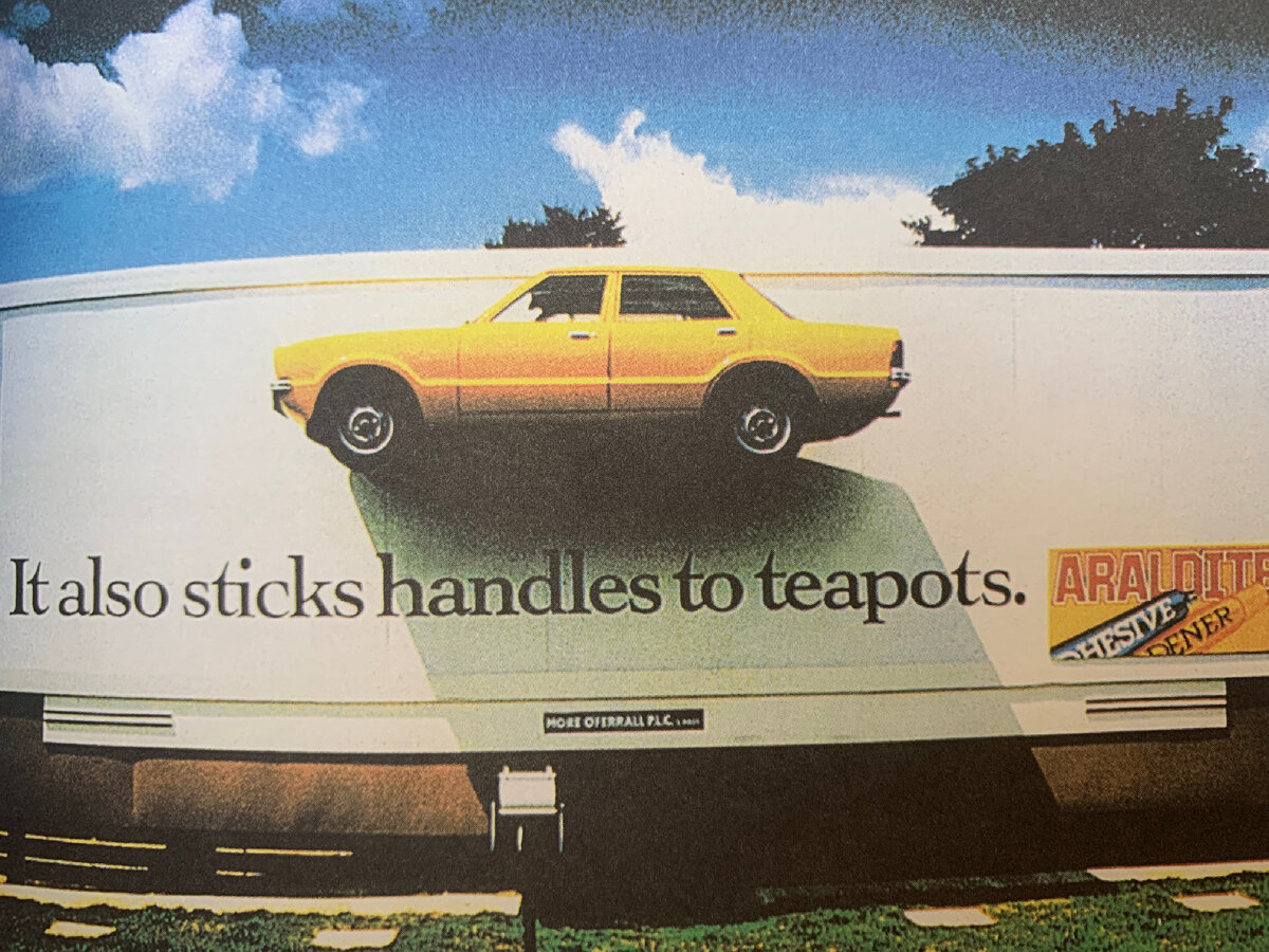 Реклама клея. Настоящая машина приклеена к рекламному щиту. «Он также приклеивает отбившуюся ручку чайника»