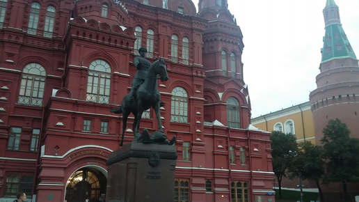 Памятник маршалу Жукову и клумбы с цветами и деревьями на площади Революции в Москве