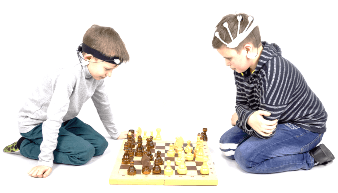 дети играют в шахматы в нейрогарнитурах NeuroPlay, записывающих данные электроактивности их мозга