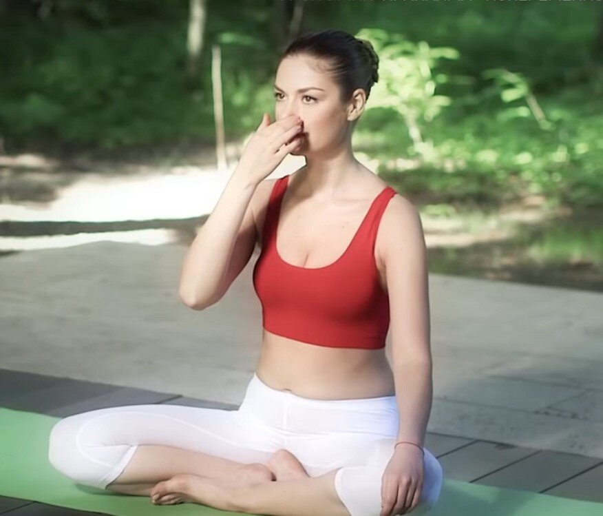 На фото выполняется одна из техник пранаяма. Девушка поочередно закрывает ноздри.