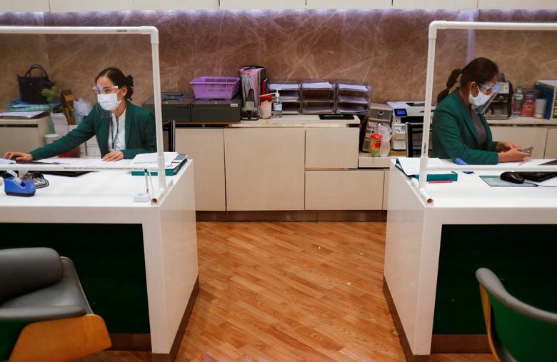 Сотрудники банка готовятся к открытию в Бангкоке, Таиланд. Они носили маски и щиты для лица