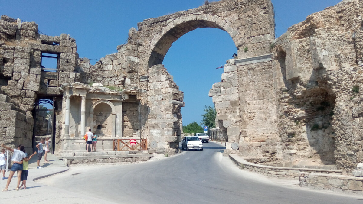 Ворота Веспасиана, рядом с которыми и находится вход в Амфитеатр. А вон та ниша, возле которой стоит человек с оранжевым рюкзаком, -- это фонтан Веспасиана. Иногда фонтан Нимфеум, о котором был рассказ в предыдущих частях, ошибочно тоже называют фонтаном Веспасиана.