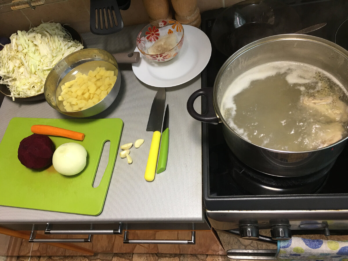 Затем чистим картофель, мелко режем кубиком и заливаем холодной водой, а то потемнеет и потеряет привлекательный вид. Так же чистим и моем лук, чеснок, морковь и свёклу. Периодически с бульона снимаем ложкой пену. 