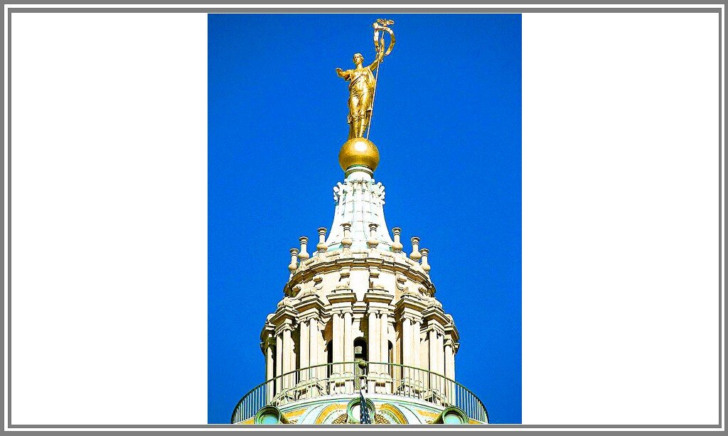 Капитолийская статуя из Гаррисберга в виде женщины (значение «женщины»: «сама любовь и мать, дающая жизнь ребенку») простирает правую руку, с открытой вниз ладонью, вперед. Как бы призывая всех, находящихся ниже неё, к успокоению, «примирению и добродетели». В левой руке она держит посох (власть у владеющего им) с орлом (острый взгляд) и гирляндой (единение, связь в единое целое). Такой посох символизирует «справедливость».