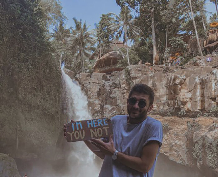 я у водопада Tegenungan Waterfall, держу доску с надписью "Я здесь, а ты нет" - удачная фотка для обложки данного поста :)