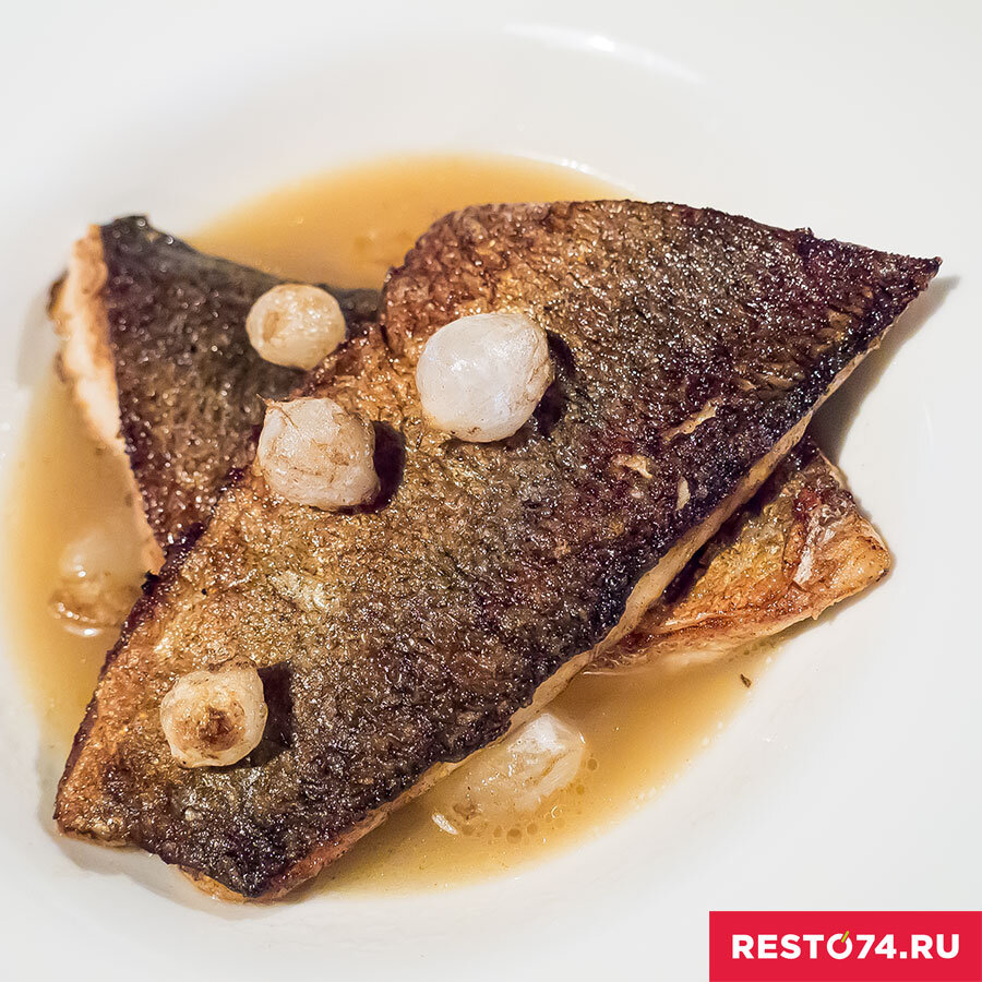 СИГ, КАРТОФЕЛЬ КОНФИ, УХА: заявленного картофеля конфи в моём блюде не оказалось. К счастью, потому что снова смею вас уверить, что как сыр в первом блюде он показался бы лишним. Зато были головки маринованного чеснока и они свежо дополнили два прекрасно поджаренных кусочка сига. Плотное и нежное белое мясо уложено наиболее живописно: шкуркой вверх. Баланс соли и специй очень выверен. Уха, а точнее – бульон, по-европейски хорош. Весьма спокойный, тонкий по аромату и вкусу. И снова мои комплименты Павлу Ческидову.