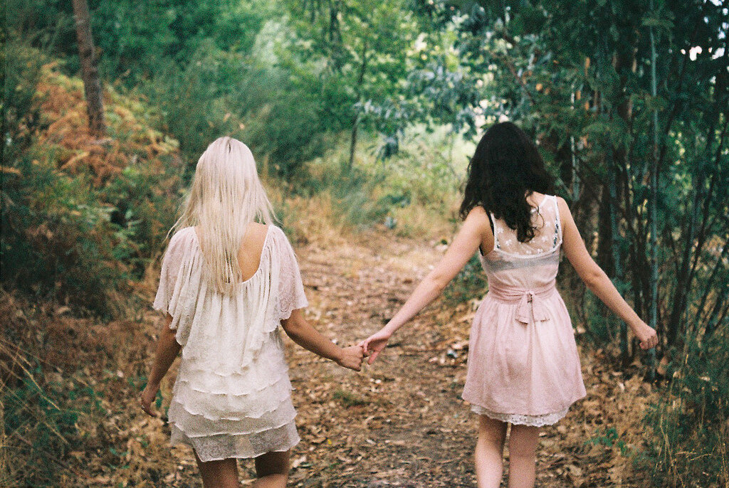 Лесбиянка пришла к девочкам. Блондинка и брюнетка подруги. Две девушки держатся за руки. Две подружки. Фотосессия подруг.