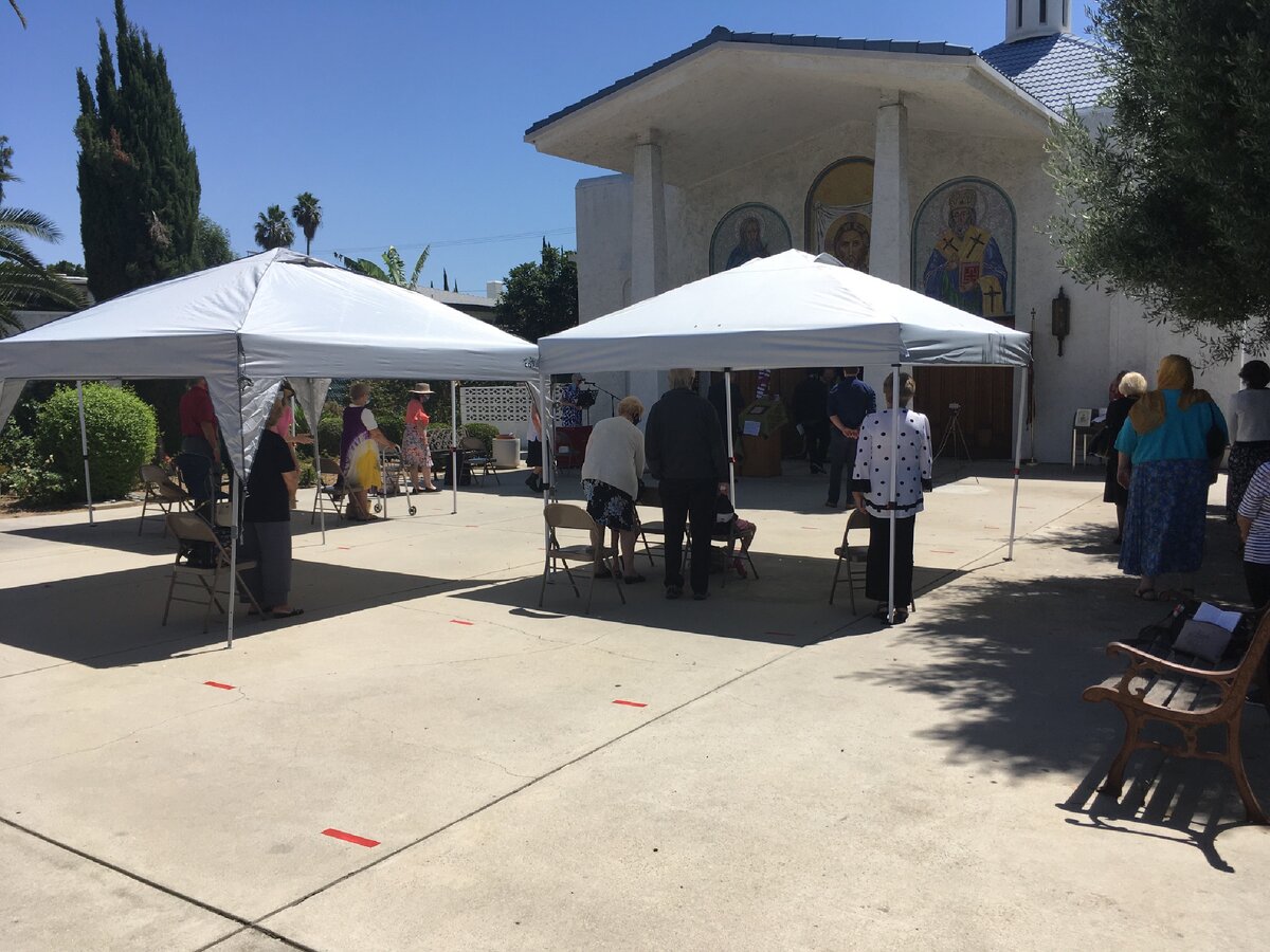 Служба проходит на улице. Предбанник переоборудован в алтарь. Батюшка в дверях. Прихожане стоят под навесами, чтобы жаркое калифорнийское солнце не напекло голову, и без того уже больную всей этой истерией. Фото автора. 