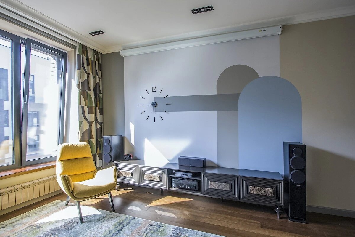 Абстрактная роспись на стене в ТВ-зоне помогает разнообразить отделку, её заказчик выбрал из нескольких вариантов.