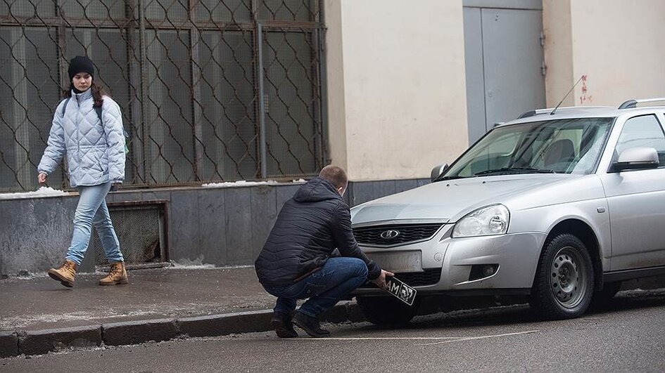 Заберут ли машину. Парень со снятыми номерами машины. Парень на парковке уличная фотография. Чем закрыть номер машины на парковке.