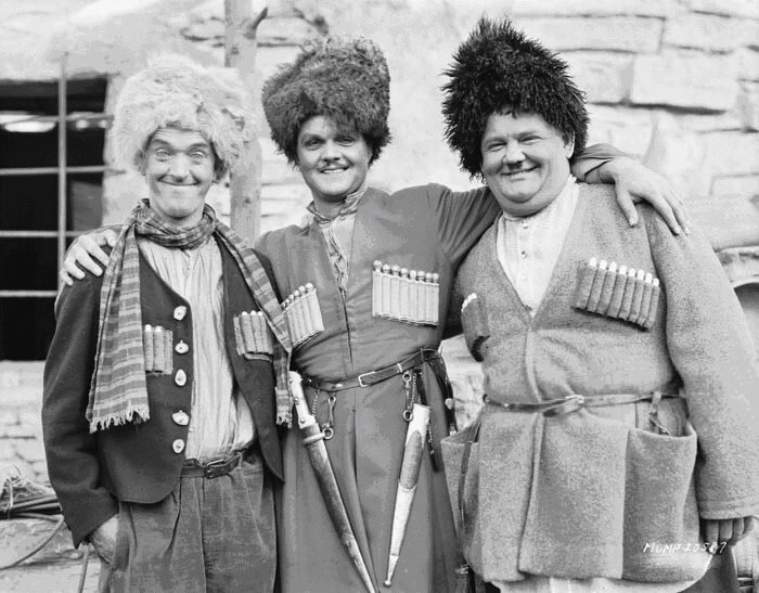 1930 США. Звезды немого кино Стэн Лорел (слева), Лоуренс Тибет и Оливер Харди (справа) в кадре из фильма «Песня о мошенничестве», в котором рассказывается о похищении девушки на Кавказе.  Режиссеры Лайонел Буримор и Халл Роуч 