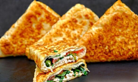 Очень быстрый рецепт невероятно вкусного перекуса – конвертики из лаваша с сочной начинкой из курицы, помидора, сыра и зелени.