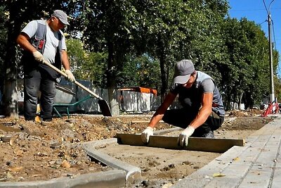    Рабочие укладывают плитку у детской площадки в сквере Защитников Родины Подольска ©Галина Добрынина Фото