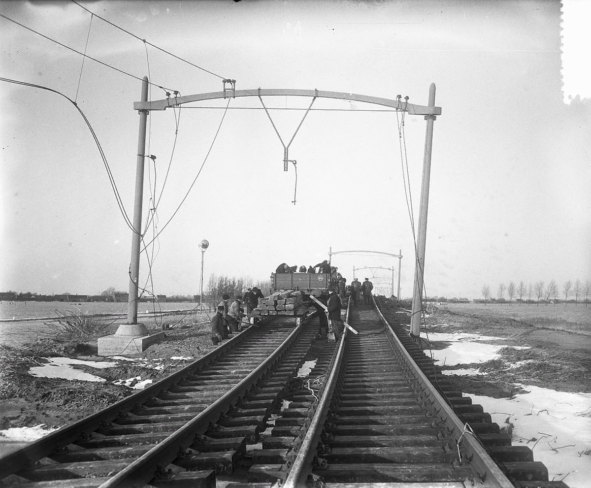 История фото 1953 года: босой мужчина несет велосипед по искореженным рельсам