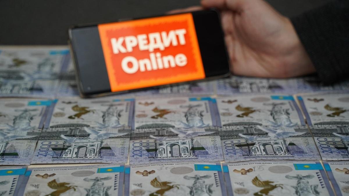    Мужчина держит в руках смартфон с надписью "Кредит Online":NUR.KZ/Владимир Третьяков