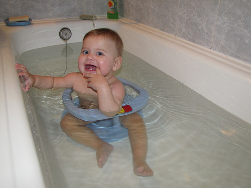 малыш сидит на пластиковом стульчике для ванны