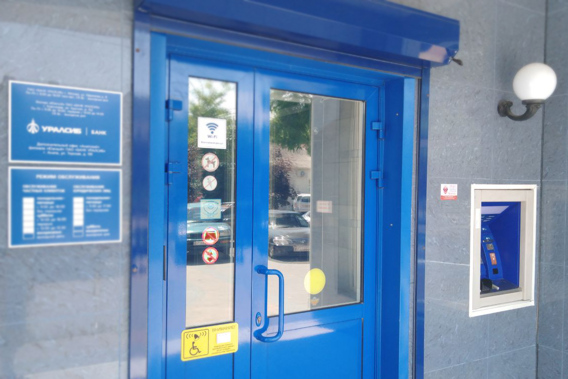 Вход в одно из отделений банка «Уралсиб» с наклейками, запрещающими вход с собаками, с мороженым и в купальных костюмах.