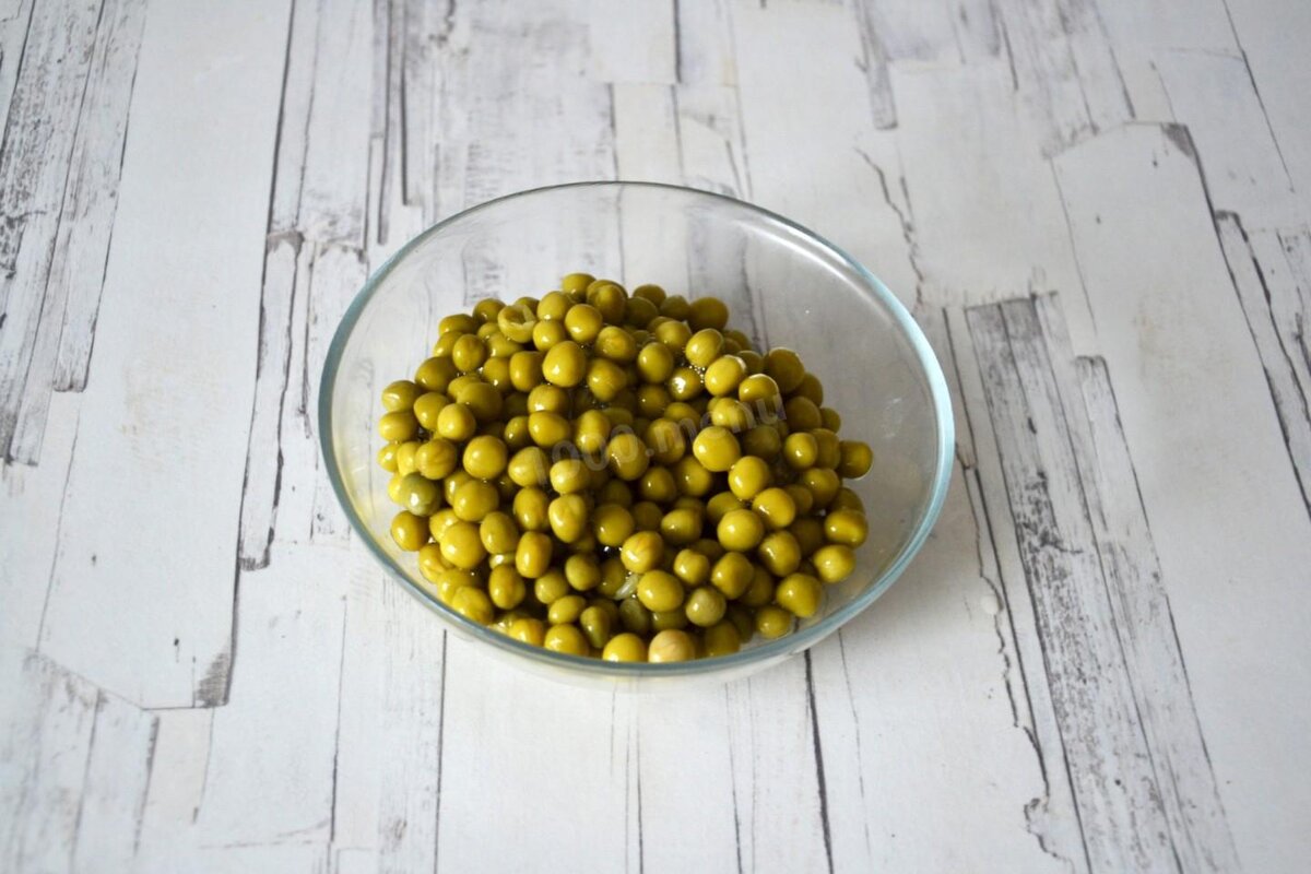 Шаг 2. Из банки зеленого горошка слейте жидкость, а сам горошек откиньте на дуршлаг и дайте полежать какое-то время. Это хорошо делать, чтобы салат не "поплыл" - мы даем всем излишкам влаги высохнуть.