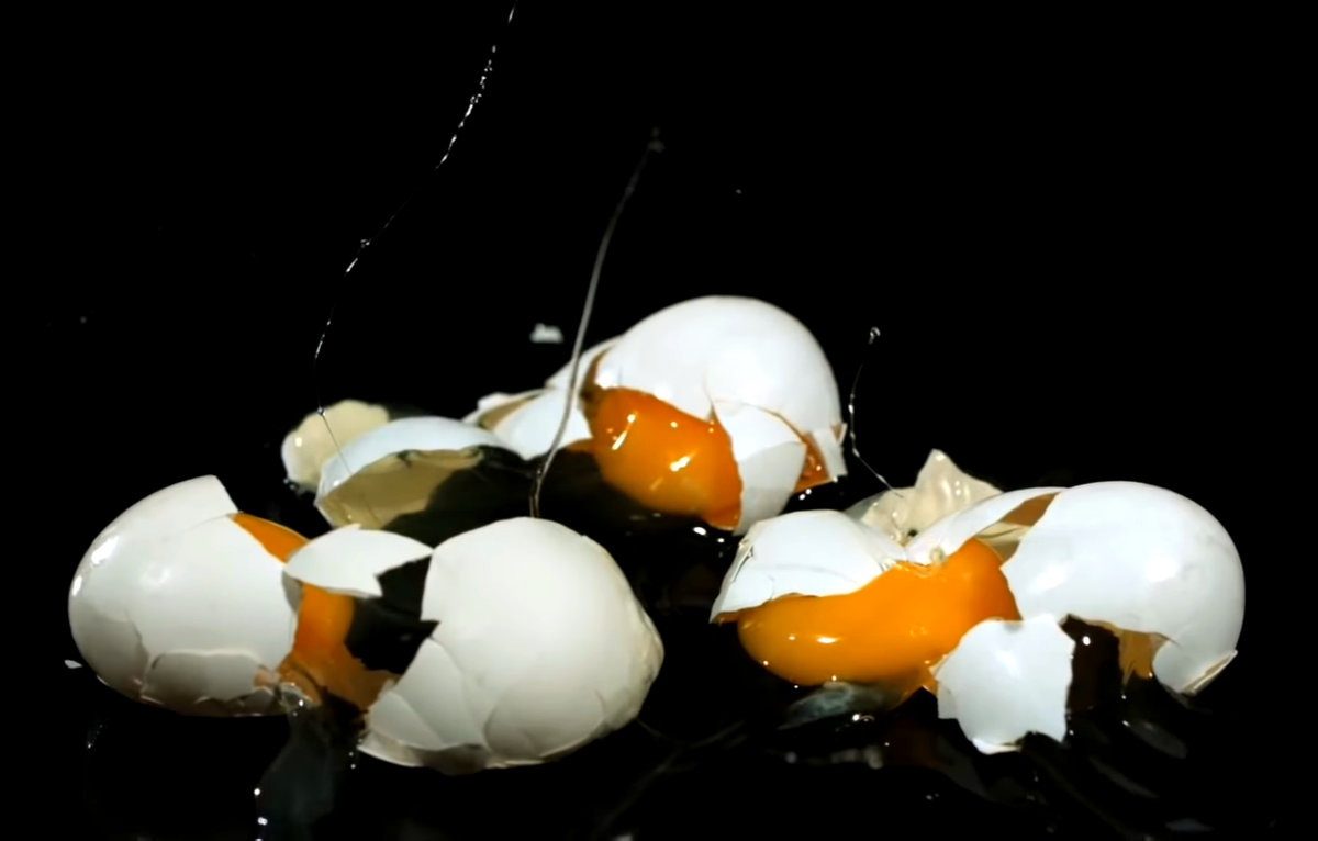 Упал яички. Разбитое яйцо. Разбитое яйцо на черном фоне. Красиво разбитое яйцо.