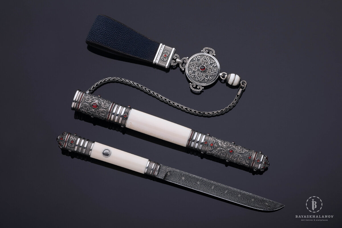 Автор: Жигжит Баясхаланов. Эксклюзивный бурятский традиционный нож "Пламя костра", 2021 г.
Материалы: Дамасская сталь, моржовый клык, бронза с гальваническим серебрением/белый металл, кожа ската, гранаты. Сайт автора: zhigzhit.com
