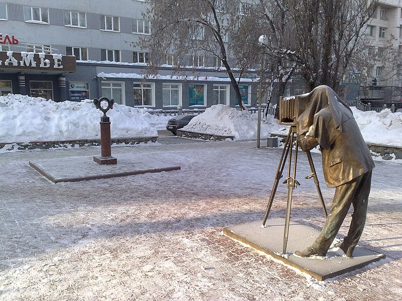 Скульптура состоит из двух частей — фигуры фотографа и круглой рамки с большими ушами, в которую фотографирующиеся могут поместить своё лицо. 
Скульптура расположена на центральной улице города Перми — Комсомольском проспекте около гостиницы «Прикамье»