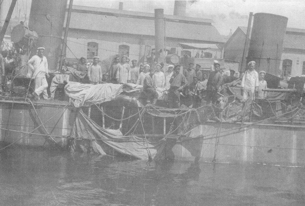 Российские моряки из команды эскадренного миноносца "Боевой" фотографируются возле пробоины, проделанной в корпусе корабля взрывом японской торпеды во время ночного сражения в бухте Тахэ. Порт-Артур, 11 июля 1904 года.